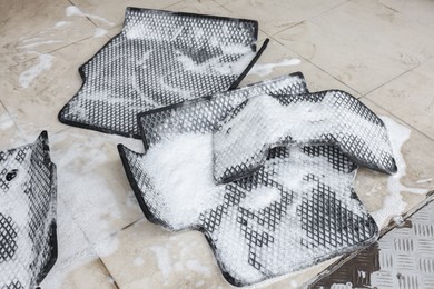 Photo of Car floor mats covered with foam indoors