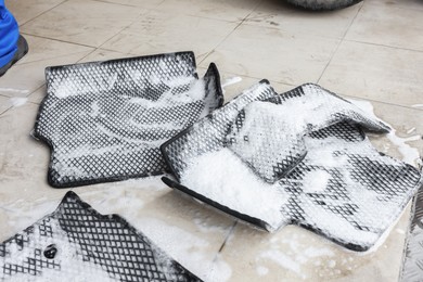 Photo of Car floor mats covered with foam indoors