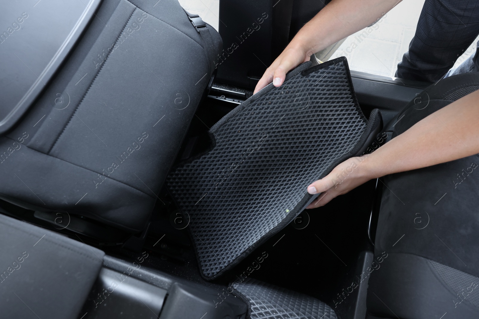 Photo of Man taking grey rubber car mat from auto, closeup