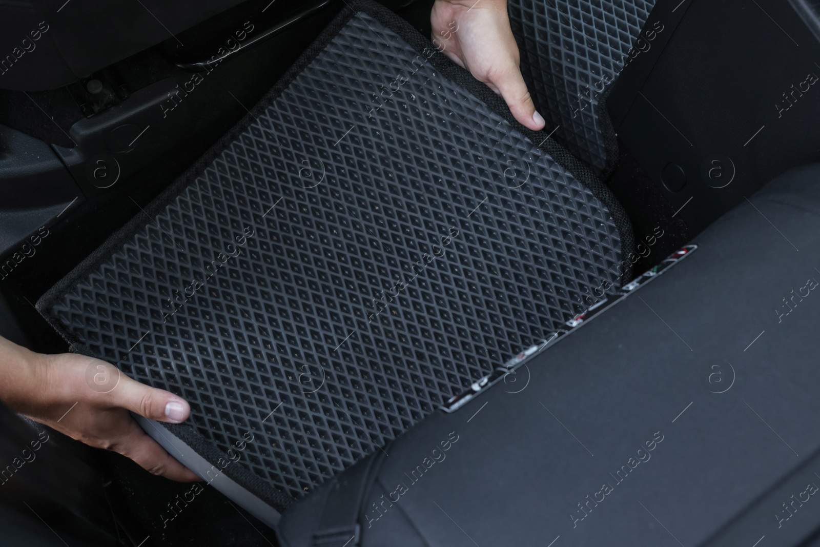 Photo of Man taking grey rubber car mat from auto, above view