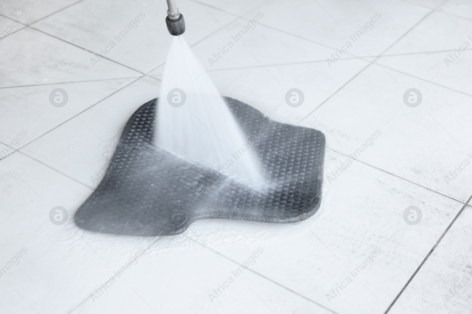 Photo of Washing rubber car mat with high pressure water jet indoors, closeup