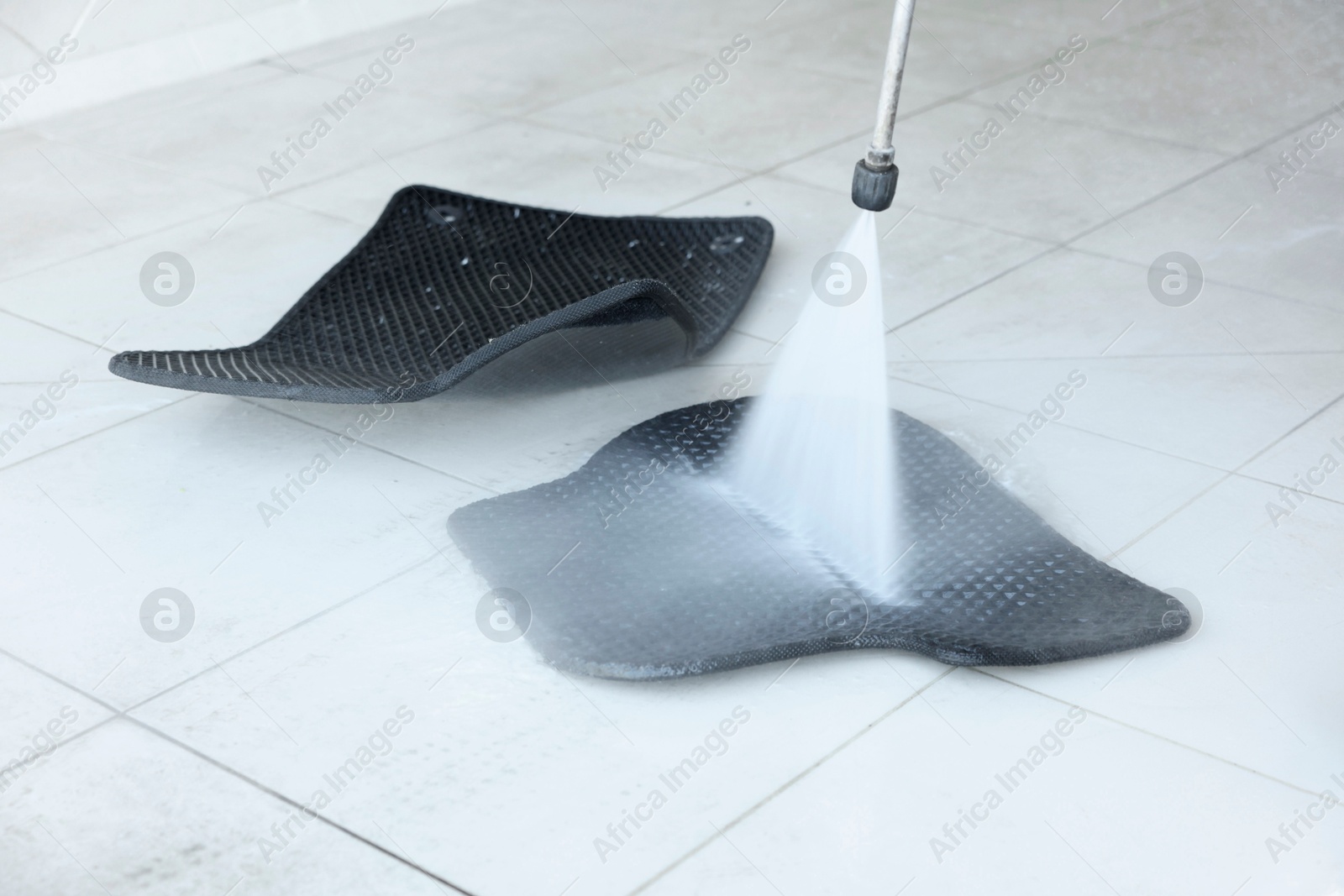 Photo of Washing rubber car mat with high pressure water jet indoors, closeup