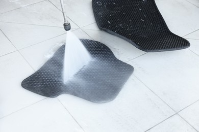 Photo of Washing rubber car mat with high pressure water jet indoors, closeup