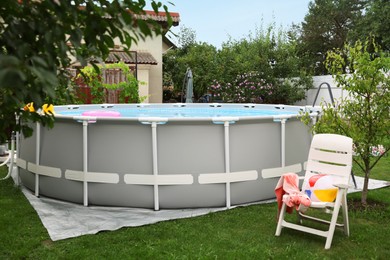 Above ground swimming pool and folding chair on grass in backyard