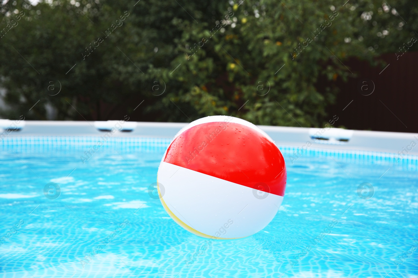 Photo of Inflatable ball floating on water in above ground swimming pool outdoors