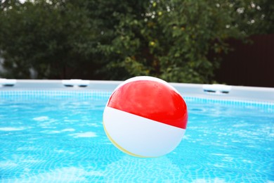 Inflatable ball floating on water in above ground swimming pool outdoors