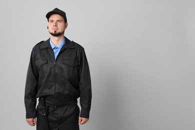 Security guard in uniform with earpiece on grey background, space for text