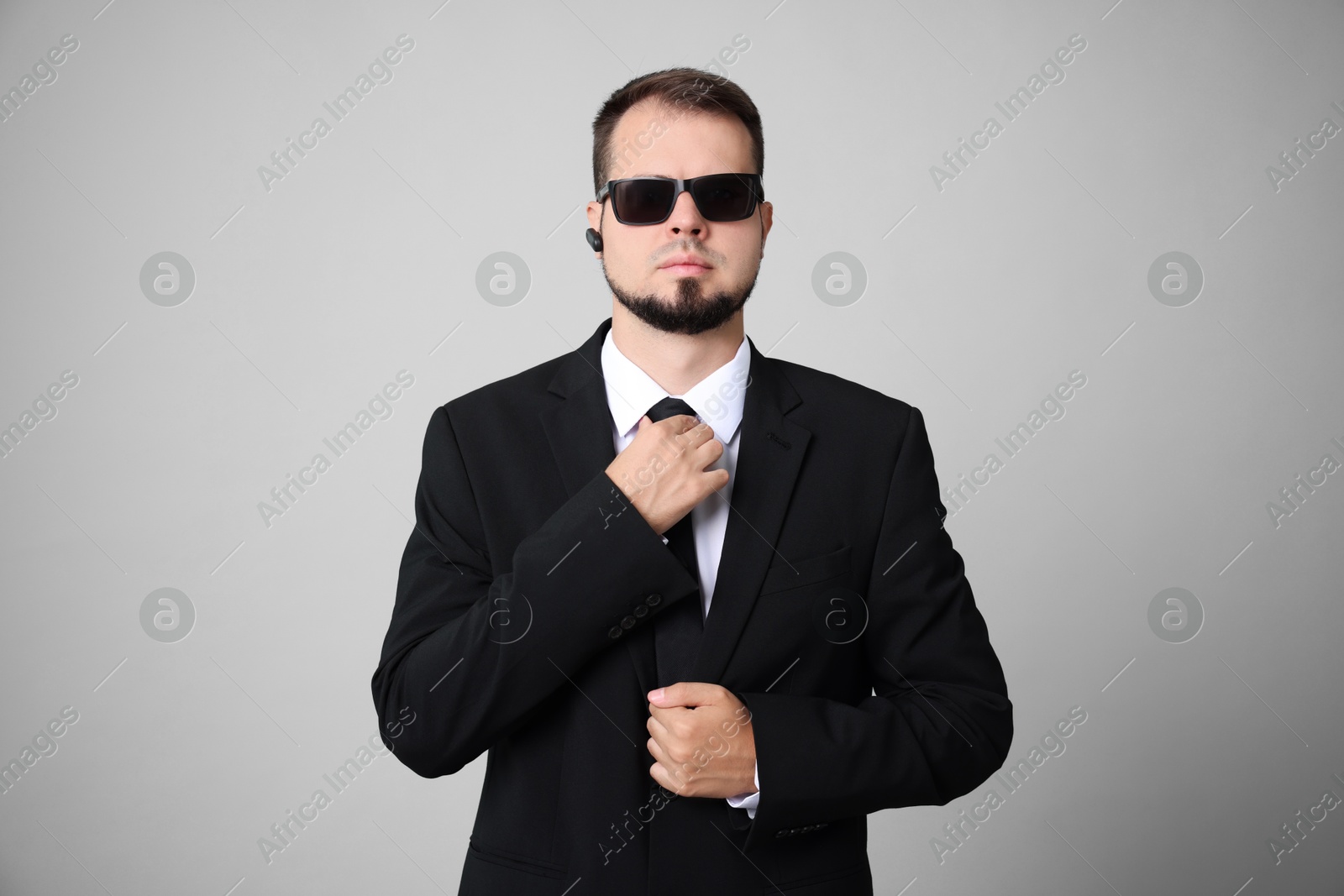 Photo of Young bodyguard in suit and sunglasses on grey background