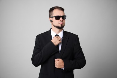 Photo of Young bodyguard in suit and sunglasses on grey background