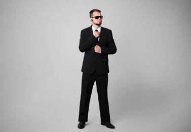 Photo of Young bodyguard in suit and sunglasses on grey background