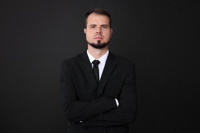 Young bodyguard in suit with earpiece on black background