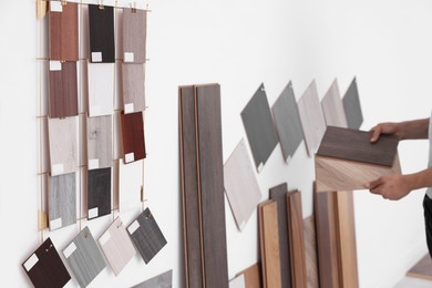 Photo of Man with different samples of wooden flooring indoors, closeup