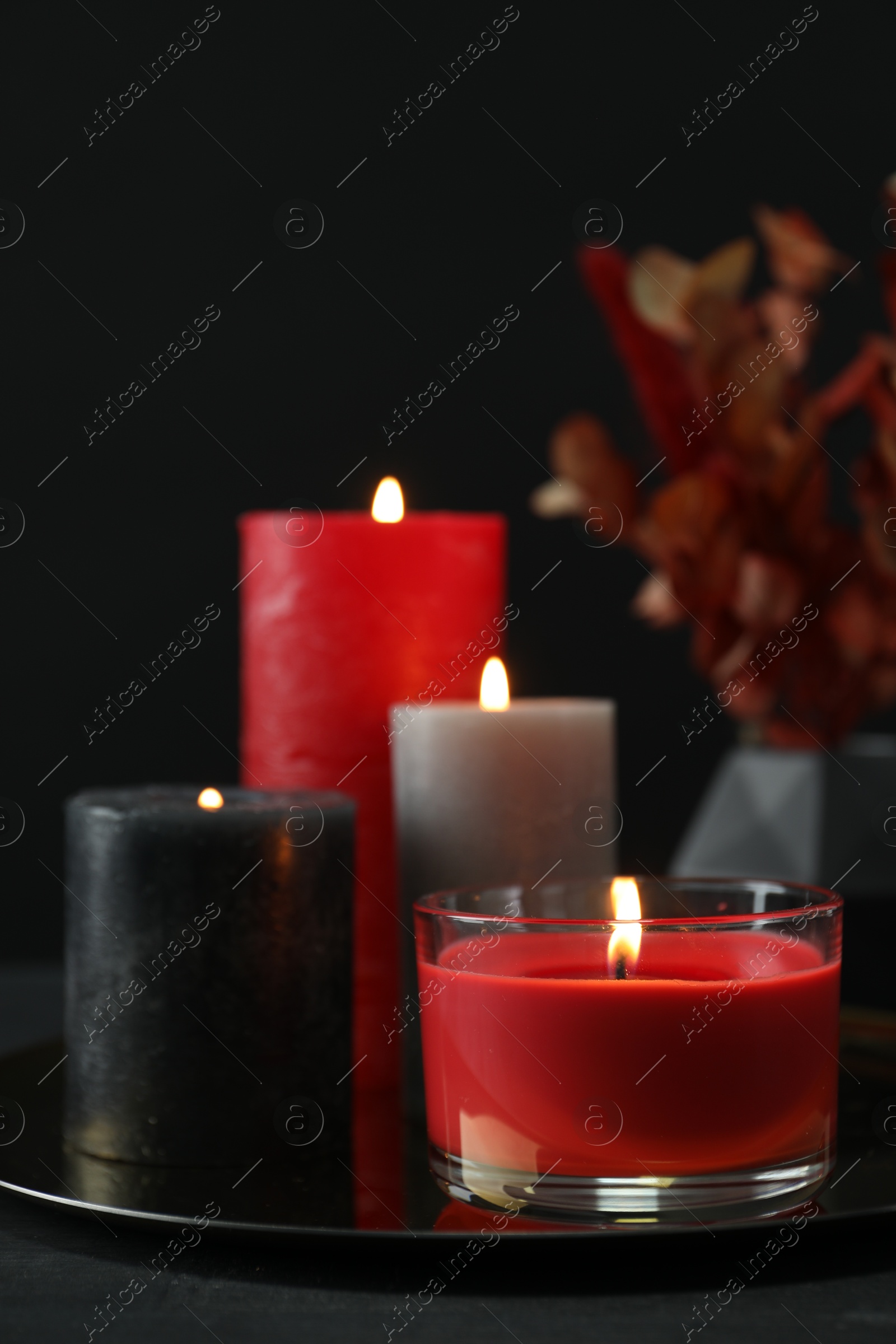 Photo of Beautiful burning candles and decor on black table, closeup