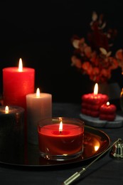 Photo of Beautiful burning candles and decor on black table, closeup