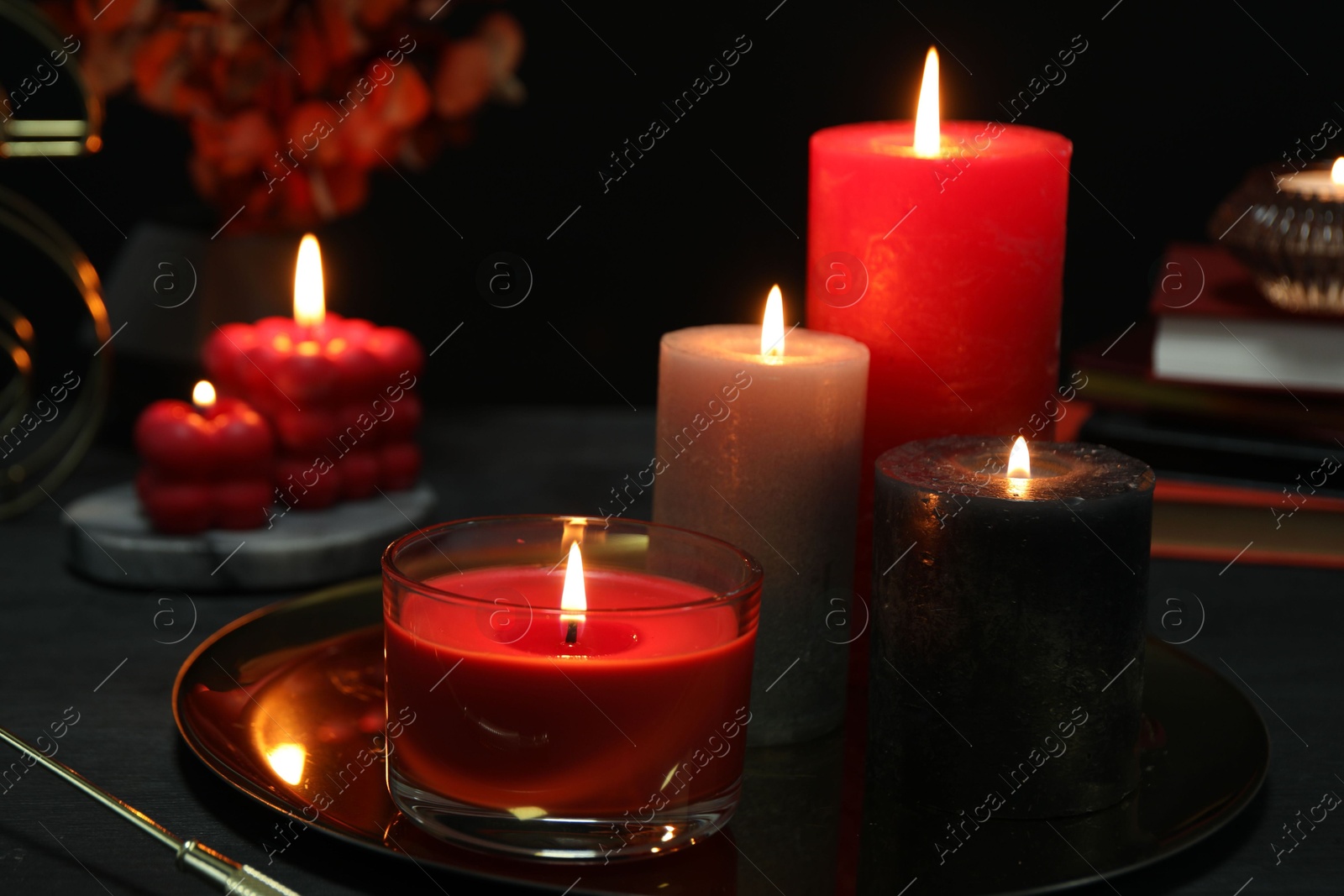 Photo of Beautiful burning candles and decor on black table, closeup