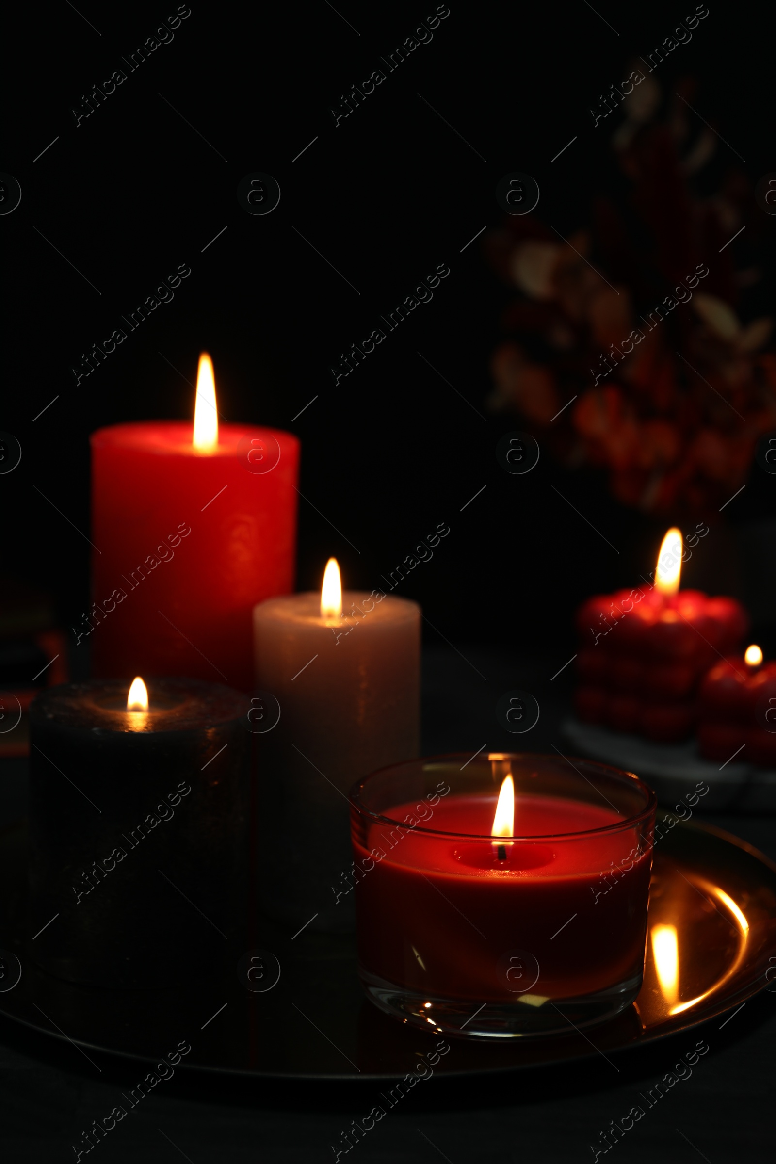 Photo of Beautiful burning candles and decor on black table, closeup