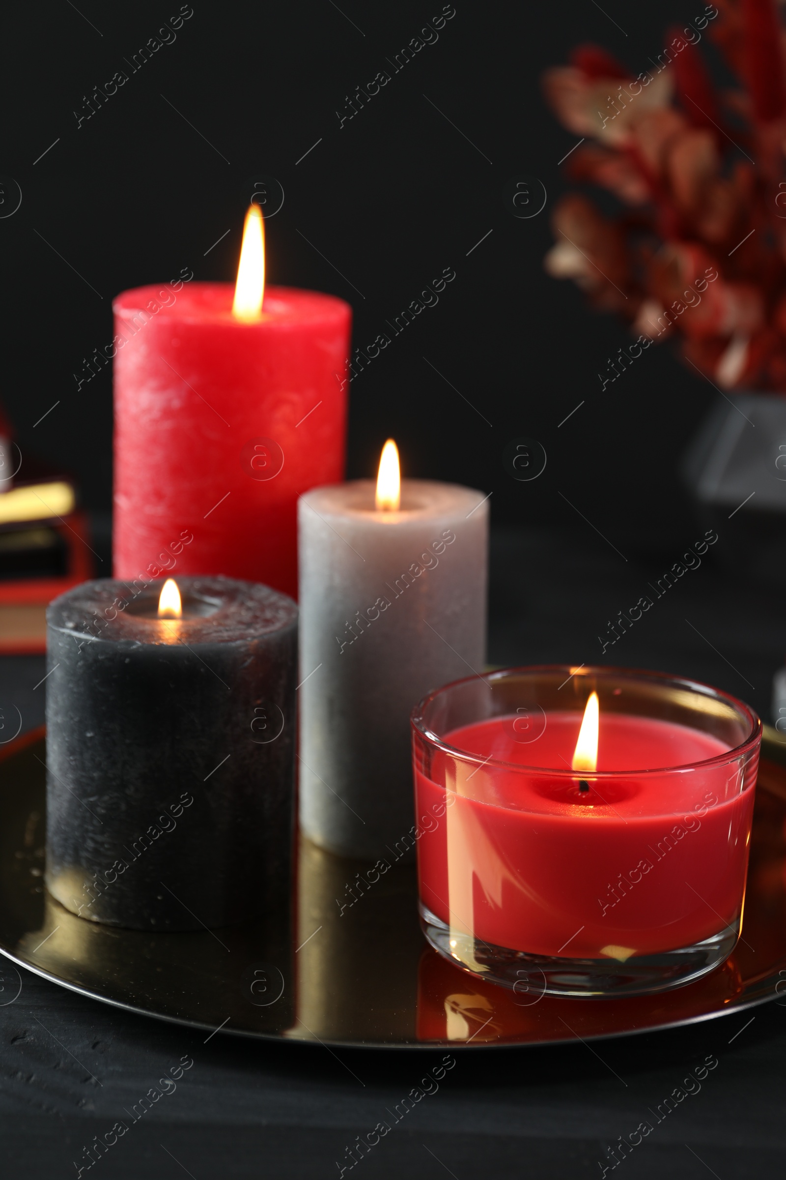 Photo of Beautiful burning candles and decor on black table, closeup