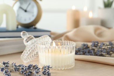 Beautiful burning candle, flowers and decor on wooden table, closeup