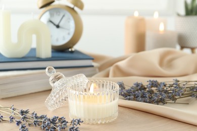 Photo of Beautiful burning candle, flowers and decor on wooden table, closeup