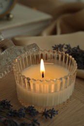 Photo of Beautiful burning candle, flowers and decor on wooden table, closeup