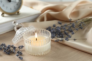 Photo of Beautiful burning candle, flowers and decor on wooden table, closeup