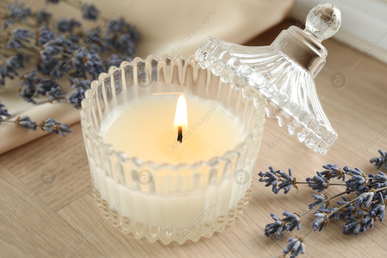 Photo of Beautiful burning candle, flowers and decor on wooden table, closeup