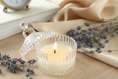 Beautiful burning candle, flowers and decor on wooden table, closeup