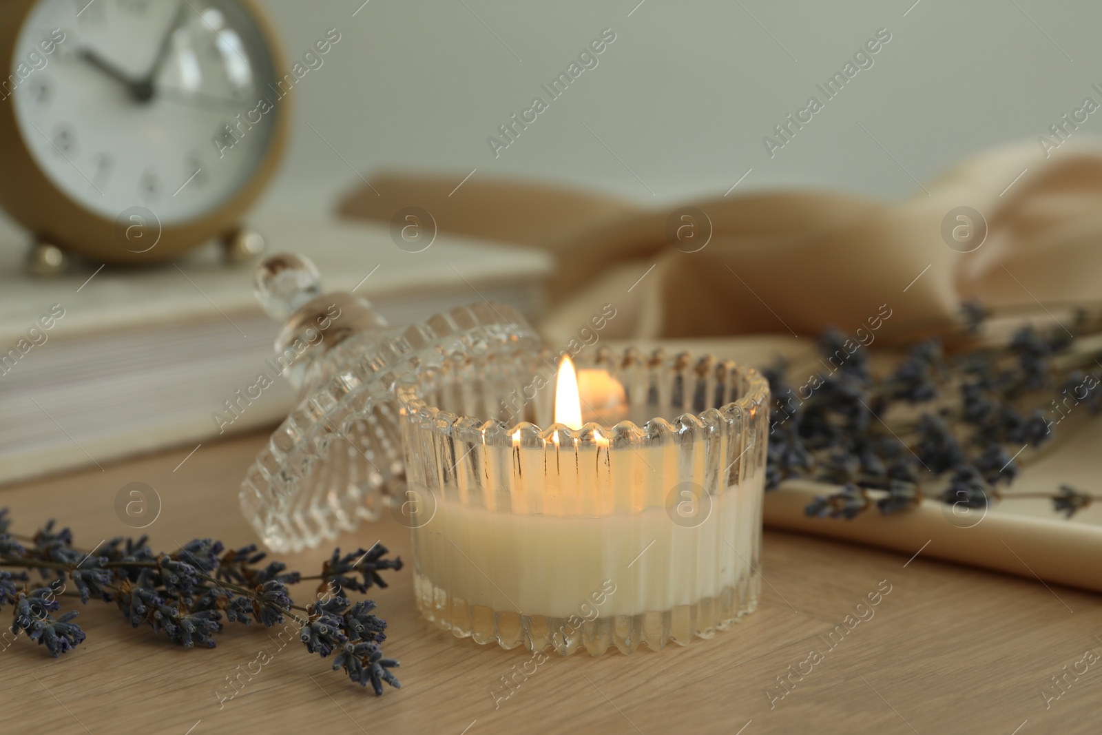 Photo of Beautiful burning candle, flowers and decor on wooden table, closeup