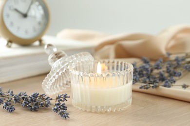 Photo of Beautiful burning candle, flowers and decor on wooden table, closeup