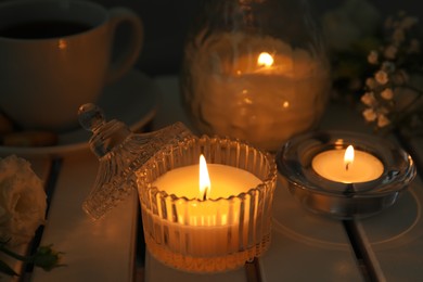 Photo of Beautiful burning candle on white wooden table, closeup