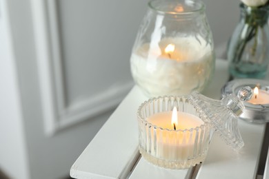 Photo of Beautiful burning candle on white wooden table, closeup. Space for text