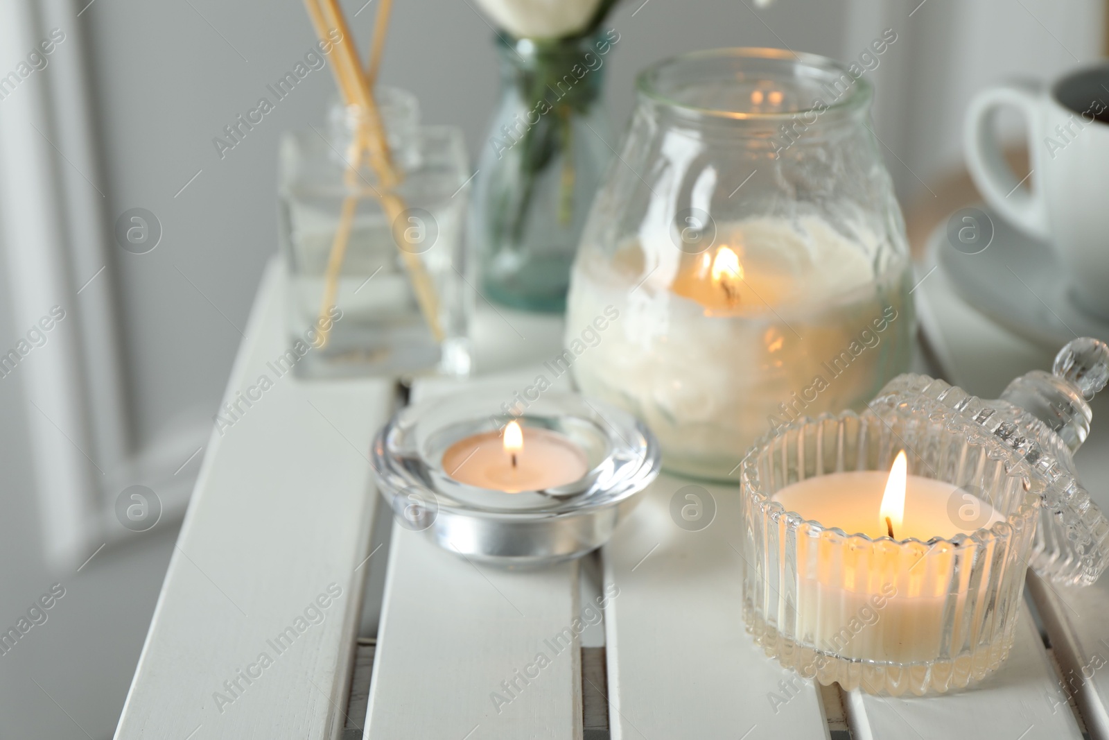 Photo of Beautiful burning candle on white wooden table, closeup