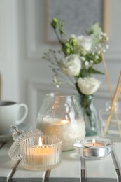 Photo of Beautiful burning candle and flowers on white wooden table