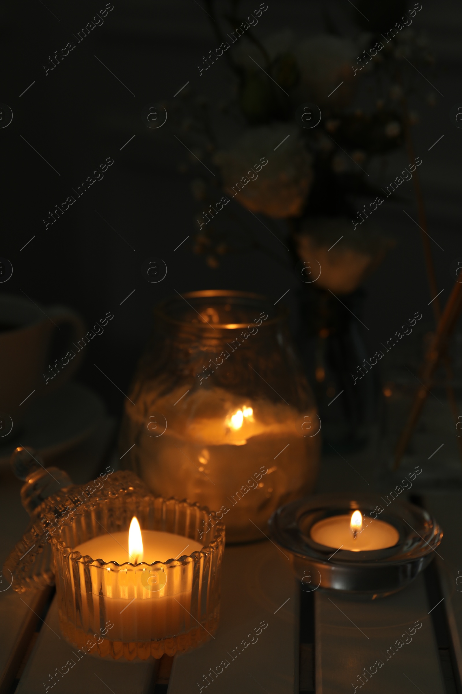 Photo of Beautiful burning candle on white wooden table, closeup