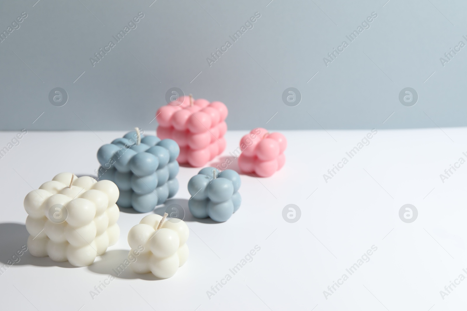 Photo of Beautiful bubble candles on white table, space for text