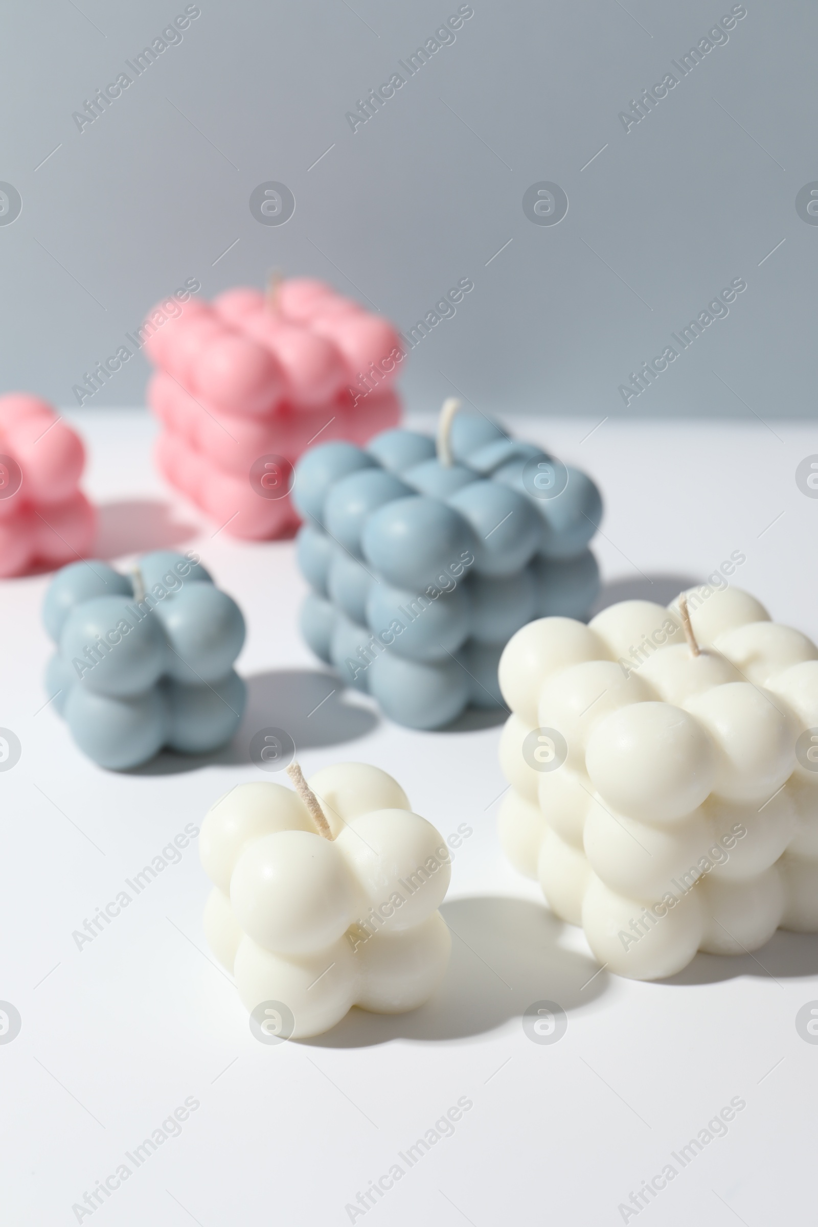 Photo of Beautiful bubble candles on white table against grey background