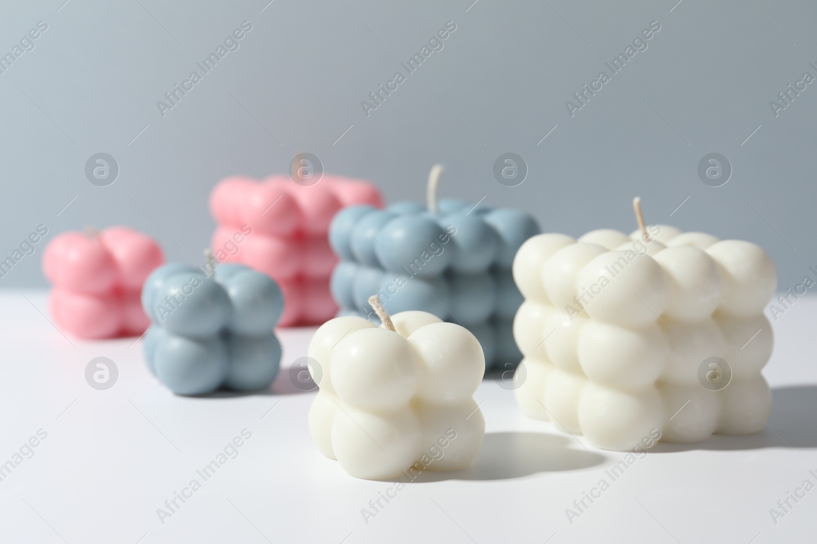 Photo of Beautiful bubble candles on white table against grey background