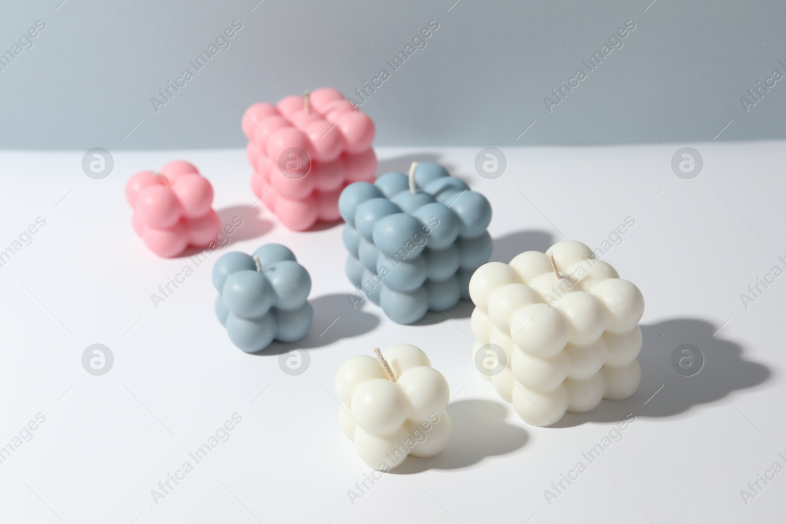 Photo of Beautiful bubble candles on white table against grey background