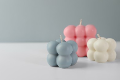 Photo of Beautiful bubble candles on white table, closeup. Space for text