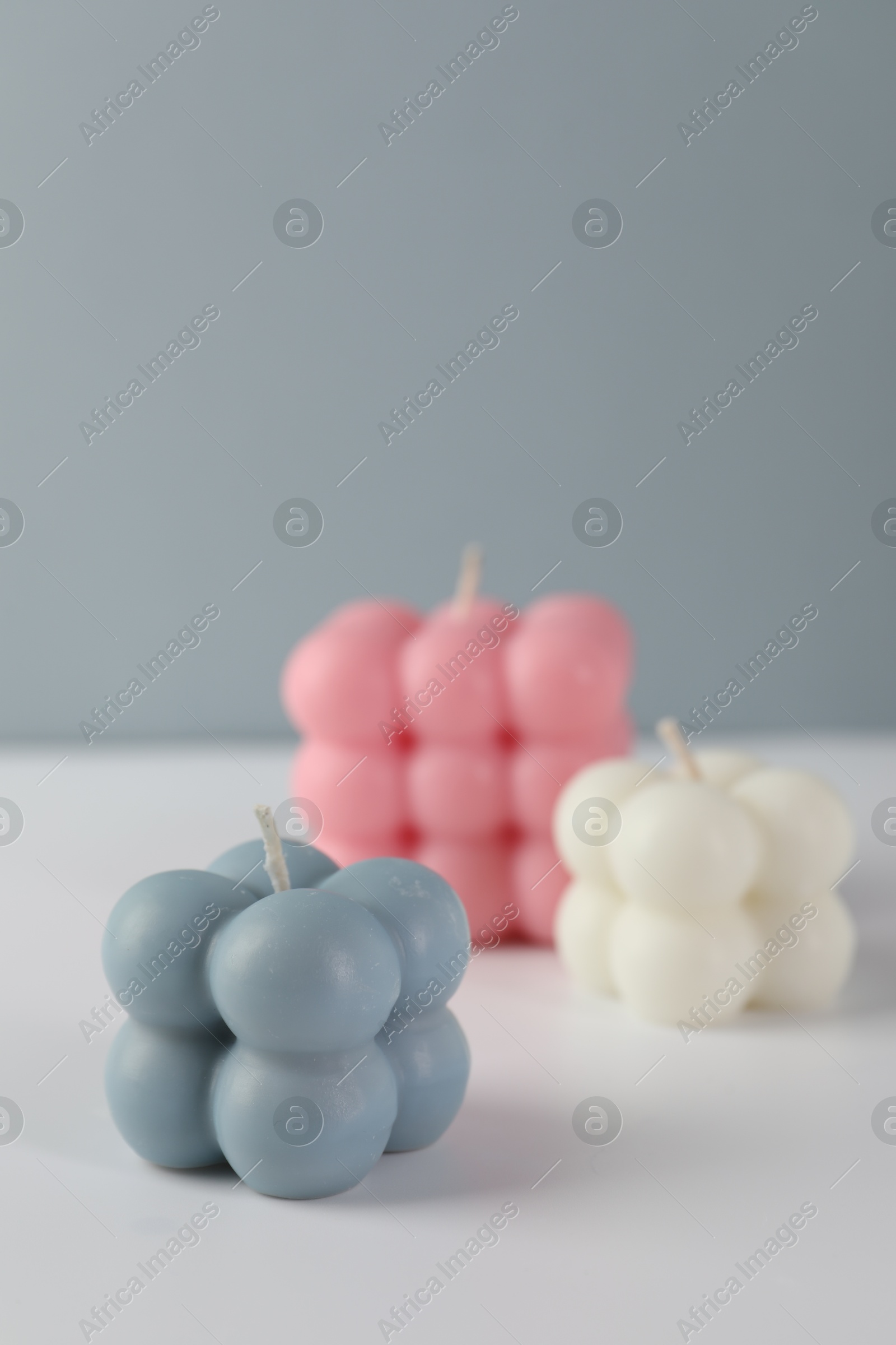 Photo of Beautiful bubble candles on white table against grey background