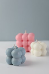 Photo of Beautiful bubble candles on white table against grey background