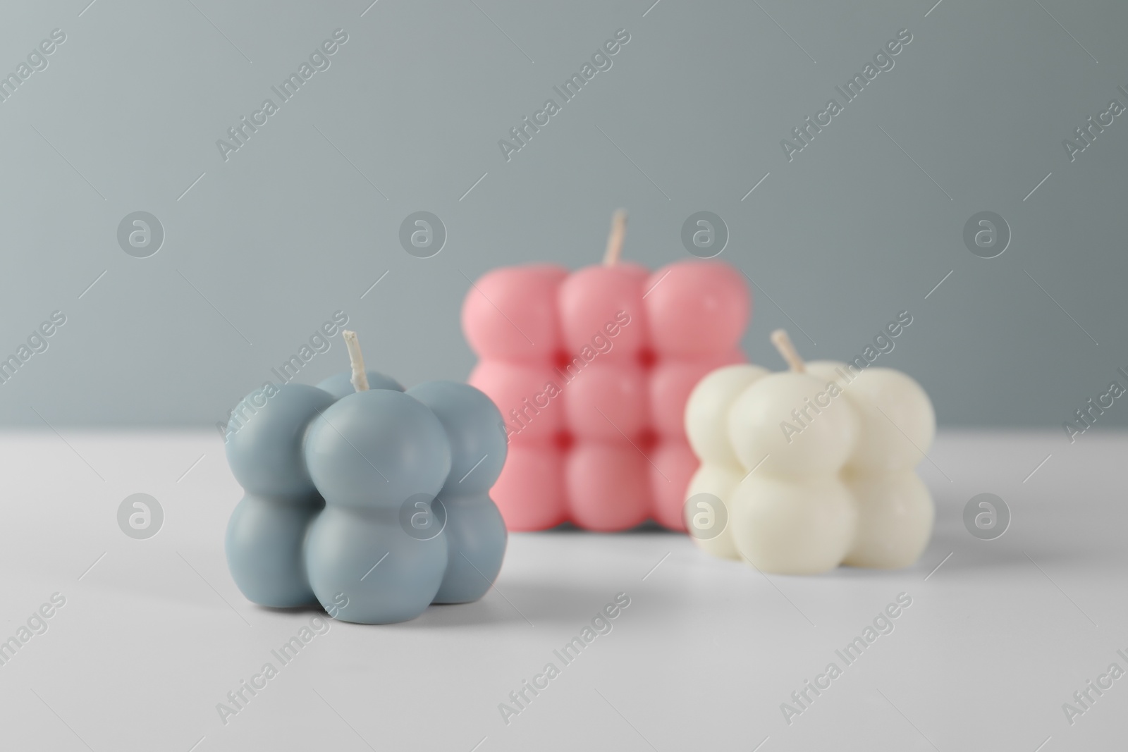 Photo of Beautiful bubble candles on white table against grey background