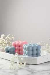 Photo of Beautiful bubble candles and flowers on white marble table