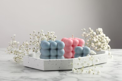 Photo of Beautiful bubble candles and flowers on white marble table