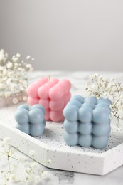 Photo of Beautiful bubble candles and flowers on white marble table