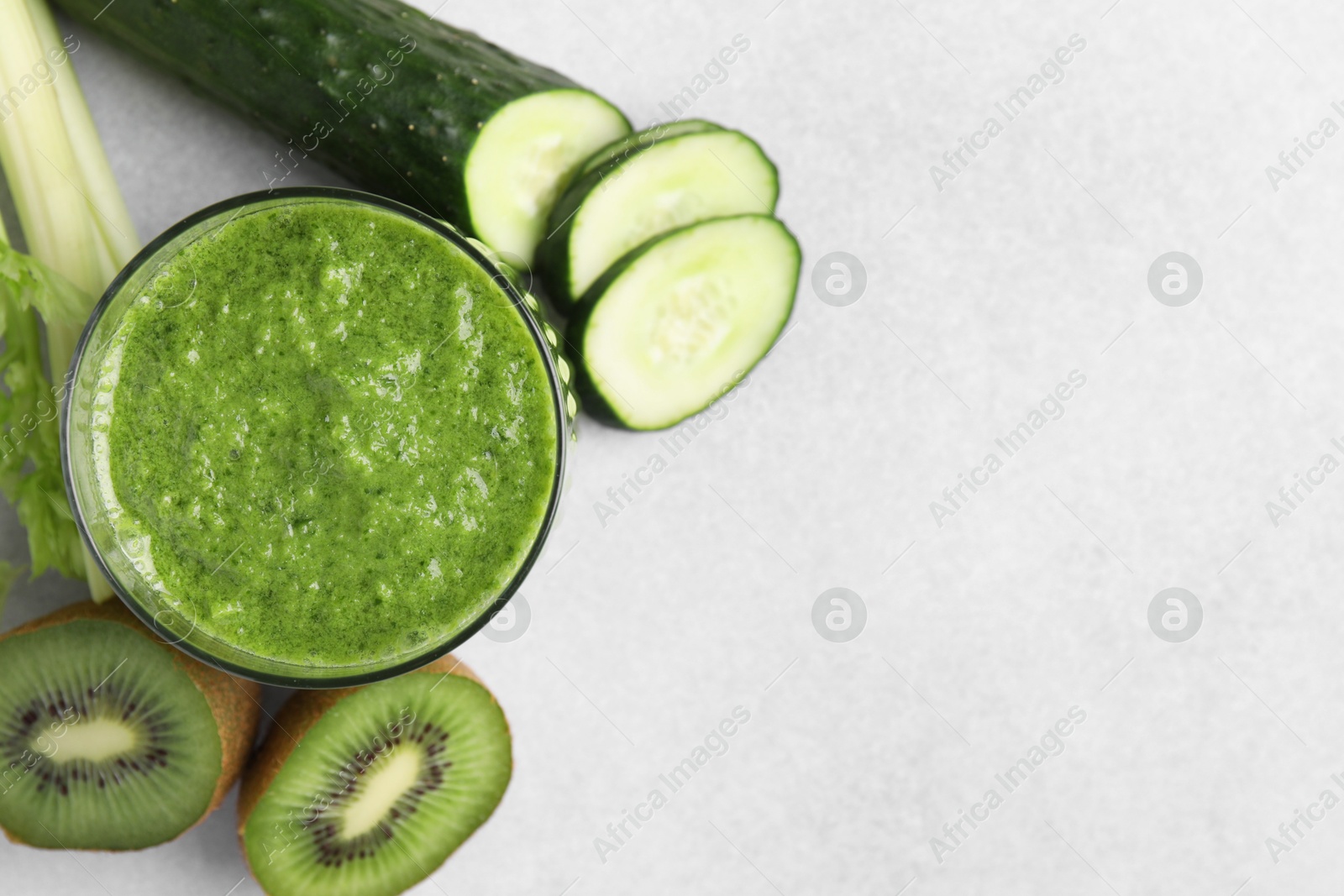 Photo of Delicious green smoothie and ingredients on light table, top view. Space for text