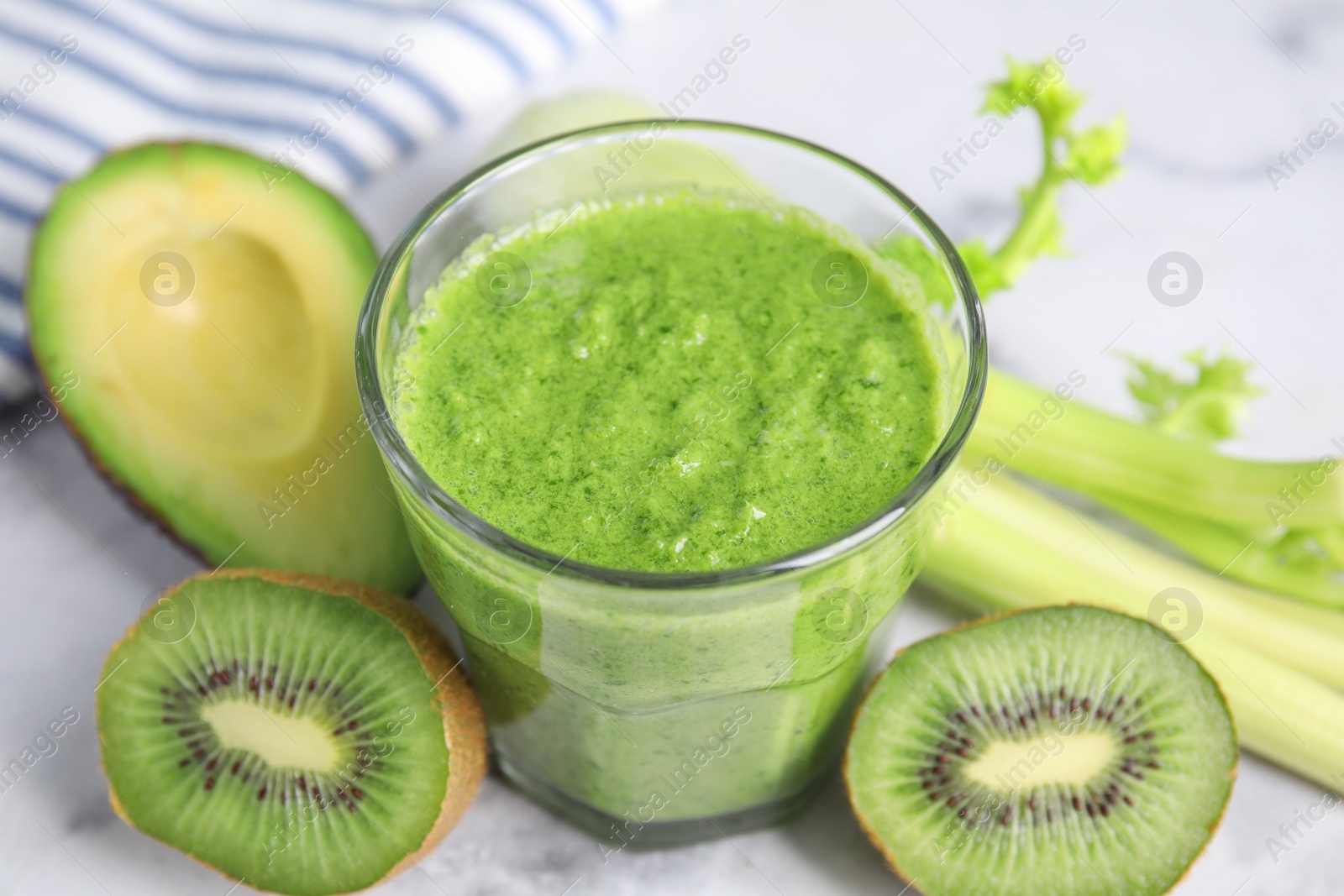 Photo of Delicious green smoothie and ingredients on white table, closeup