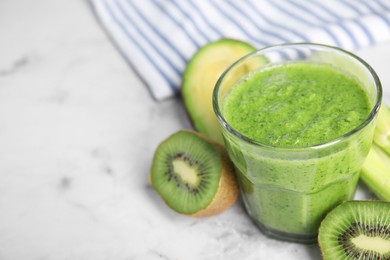 Photo of Delicious green smoothie and ingredients on white marble table, closeup. Space for text