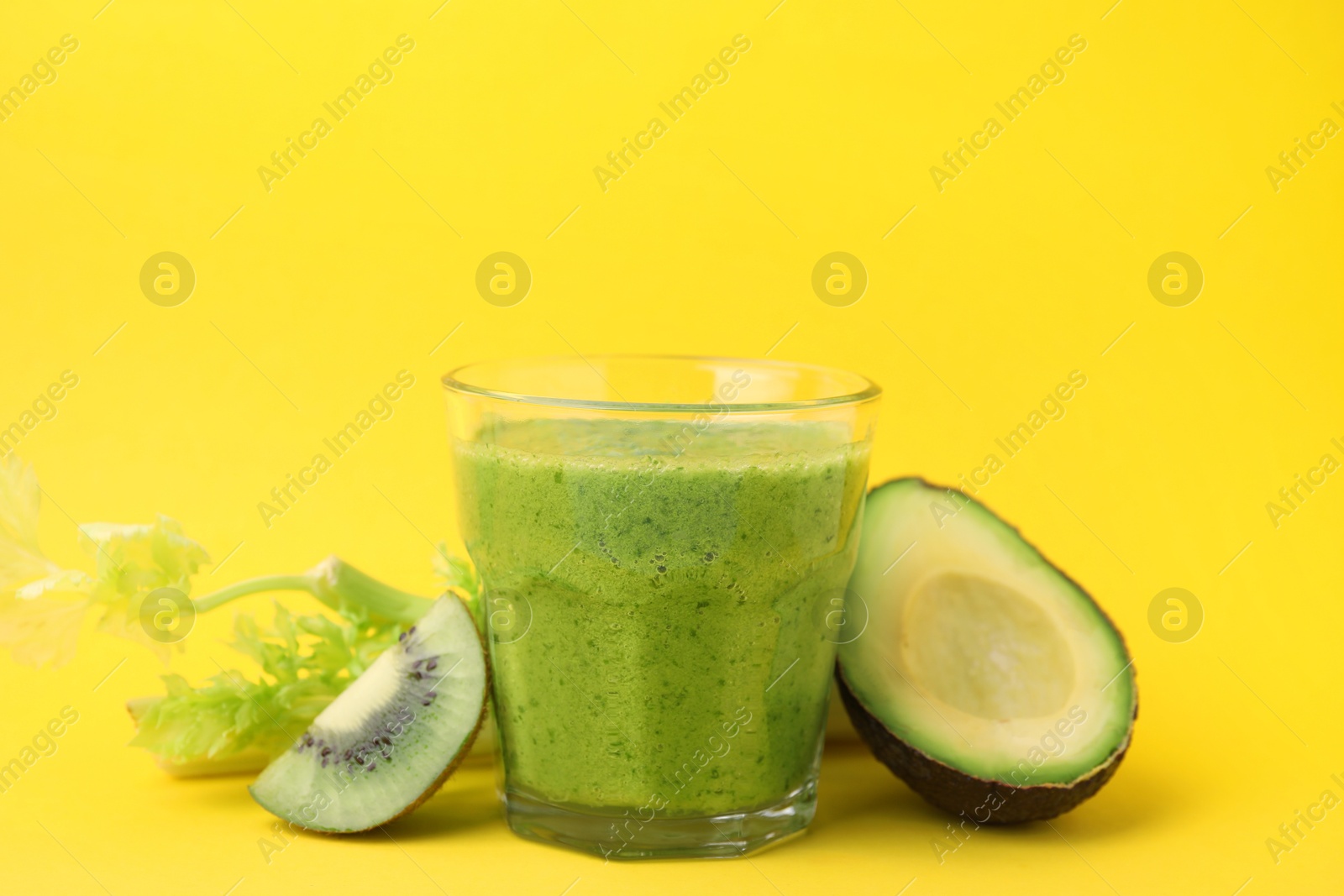 Photo of Delicious green smoothie and ingredients on yellow table