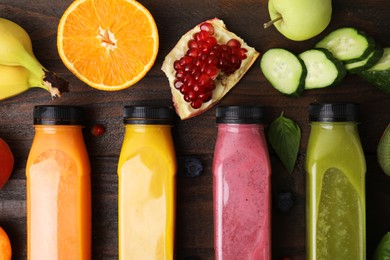 Photo of Glass bottles of tasty smoothies and different products on wooden table, flat lay